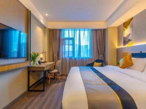 a hotel room with a bed and a desk and a television at Home Inn Kunming Baita Road in Kunming