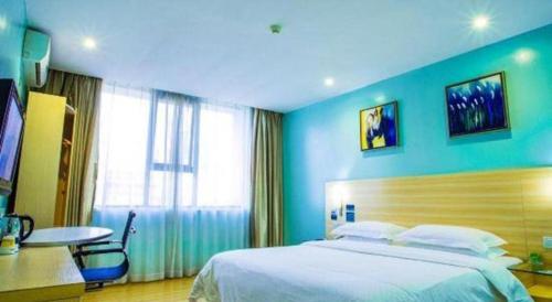 a bedroom with a large bed and a blue wall at City Comfort Inn Guilin Xing'an in Xing'an