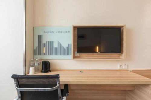 a room with a desk with a television on a wall at City Comfort Inn Xiangyang Railway Station in Xiangyang