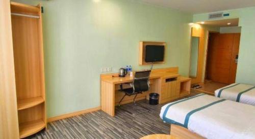 a hotel room with a desk and a bed and a television at City Comfort Inn Guilin Xing'an in Xing'an