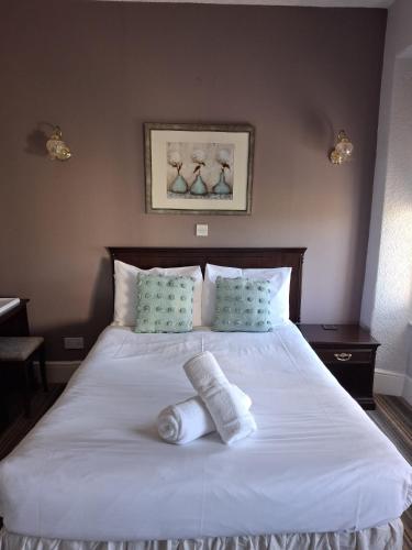 a bedroom with a large white bed with towels on it at The Cambrian in New Quay