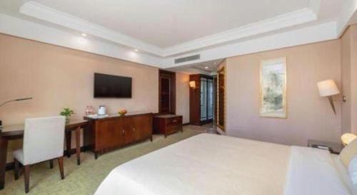 a hotel room with a bed and a desk and a television at Chinflux Mandarin Hotel in Dongguan