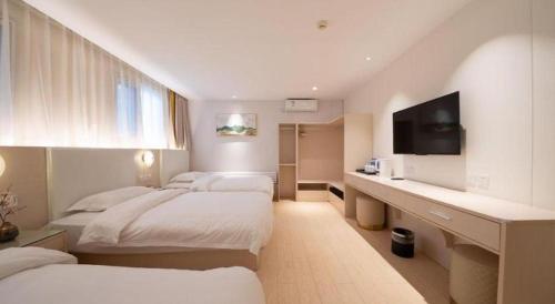 a hotel room with three beds and a desk with a television at Beijing Inner Mongolia Hotel Chaoyang in Beijing