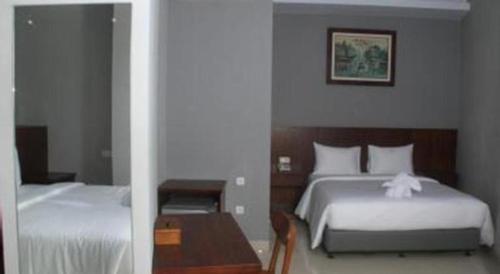 a hotel room with two beds and a table at HOTEL GRAND KUTILANG SYARIAH in Bandar Lampung