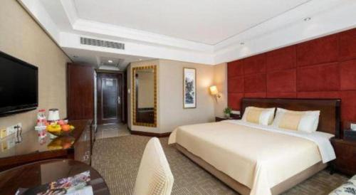 a hotel room with a large bed and a table at Chinflux Mandarin Hotel in Dongguan