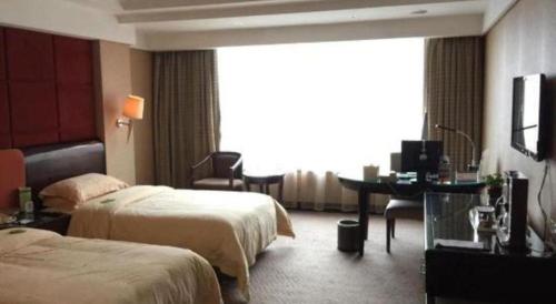 a hotel room with two beds and a desk at Chinflux Mandarin Hotel in Dongguan