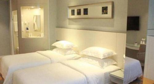 a bedroom with two beds with white sheets and pillows at Zaozhuang Hotel in Zaozhuang