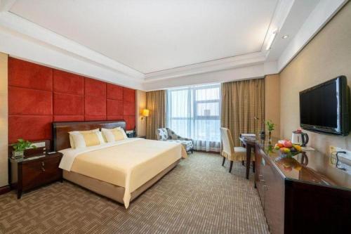 a hotel room with a bed and a flat screen tv at Chinflux Mandarin Hotel in Dongguan