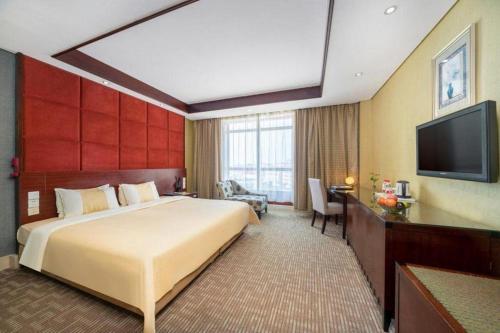 a hotel room with a large bed and a flat screen tv at Chinflux Mandarin Hotel in Dongguan