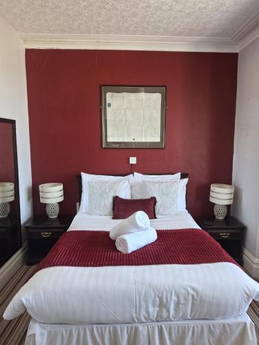 a bedroom with a large bed with a red wall at The Cambrian in New Quay