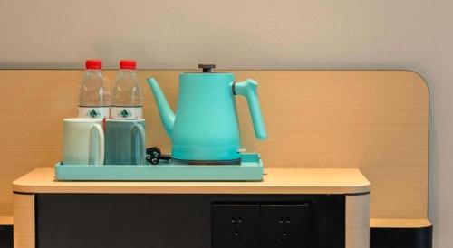a blue tea kettle and two bottles of water on a table at City Comfort Inn Wuhan Hankou Railway Station West Square in Wuhan