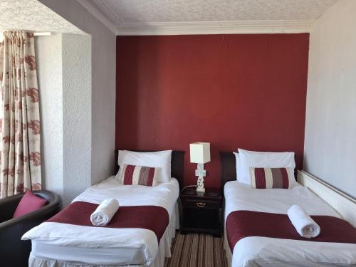 a hotel room with two beds and a red wall at The Cambrian in New Quay