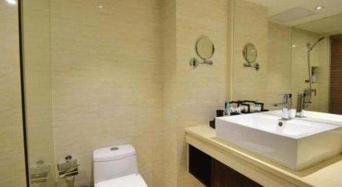 a bathroom with a sink and a toilet and a mirror at Oriental Hotel in Dongguan
