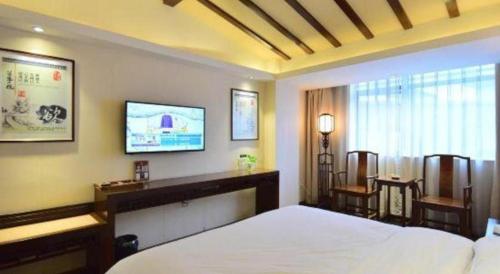 a bedroom with a bed and a tv on the wall at Oriental Hotel in Dongguan