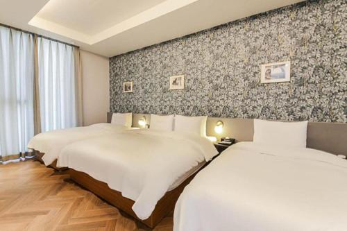 two beds in a hotel room with a wall at Gimhae Perfect Hotel in Gimhae