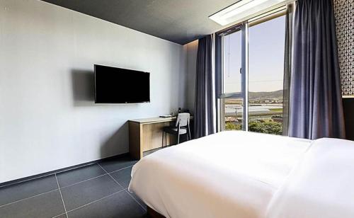 a hotel room with a bed and a television at Gimhae Perfect Hotel in Gimhae