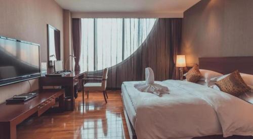 a hotel room with a bed and a desk and a television at Kunming Wenhui Hotel in Kunming