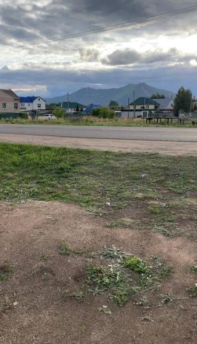 a field of grass next to a road at Экохаус Бурабай 1 in Borovoye