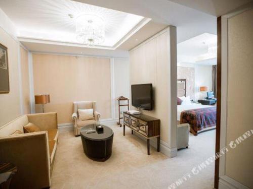 a living room with a bed and a room with a television at Fortune International Hotel in Xiawutun