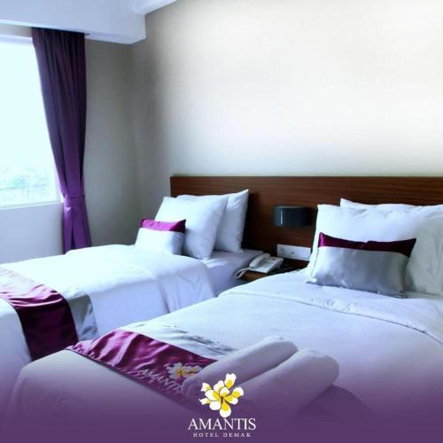 two beds in a hotel room with purple and white at Amantis Hotel in Demak