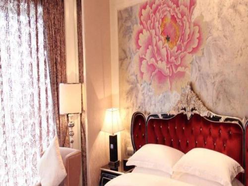 a bedroom with a bed with a flower painting on the wall at Fortune International Hotel in Xiawutun