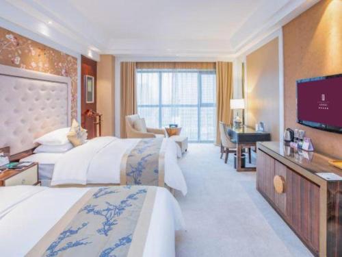 a hotel room with two beds and a flat screen tv at Fortune International Hotel in Xiawutun