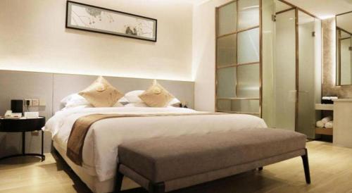 a bedroom with a large white bed with a bench at Fliport Garden Hotel Nanjing in Nanjing