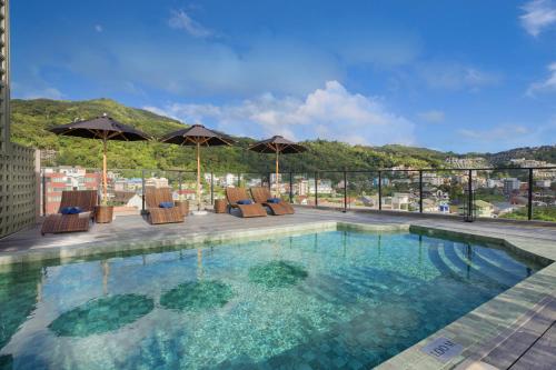 a swimming pool with chairs and umbrellas on a building at Syama Mansion Patong, an Aspira Collection in Patong Beach
