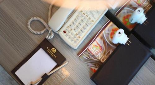 a desk with a keyboard and a book and a phone at Jinjiang Metropolo Hotel - Qingdao Chengyang District Government in Qingdao