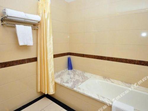 a bathroom with a tub with a shower curtain at Guangzhou Jing Yi hotel in Huadu
