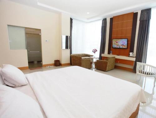 a bedroom with a large white bed and a living room at Plaza Hotel Tegal in Tegal