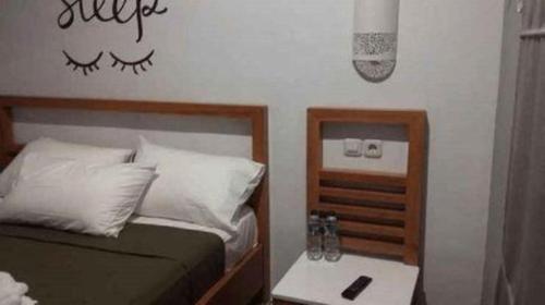 a bedroom with a bed and a table with a phone at InnBox Capsule Hotel in Jember
