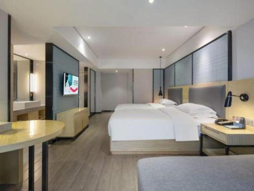 a hotel room with a large bed and a television at Echarm Hotel Beihai Railway Station in Beihai