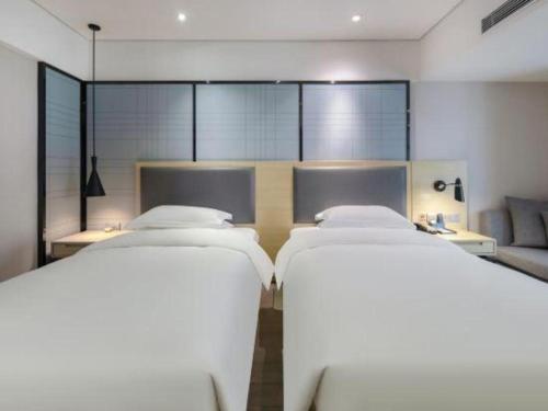 two beds in a room with a couch at Echarm Hotel Beihai Railway Station in Beihai