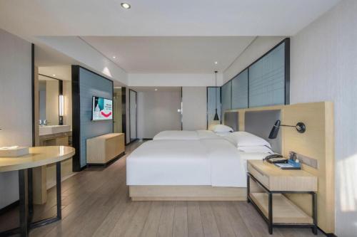 a bedroom with a large white bed and a desk at Echarm Hotel Beihai Railway Station in Beihai