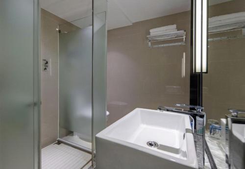 a bathroom with a white sink and a shower at Echarm Hotel Beihai Railway Station in Beihai