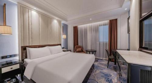 a hotel room with a large white bed and a desk at Jinjiang Metropolo Hotel Nanjing Confucius Temple Branch in Nanjing