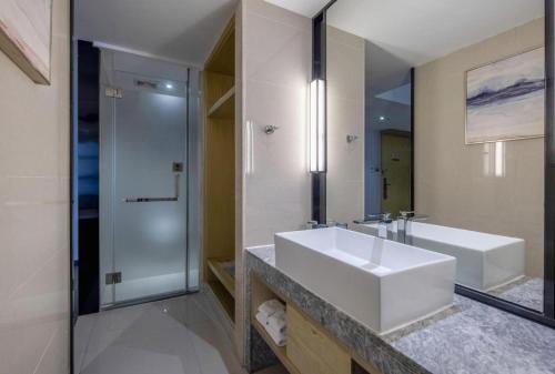 a bathroom with a white sink and a shower at Echarm Hotel Beihai Railway Station in Beihai