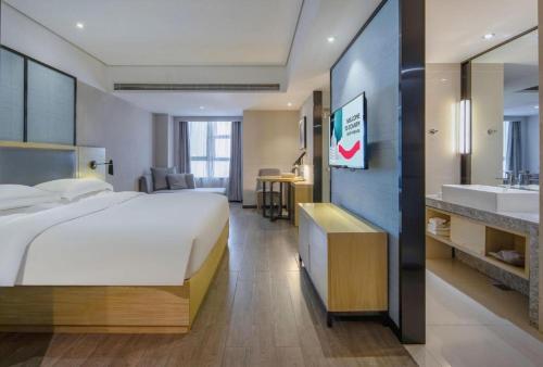 a hotel room with a large bed and a sink at Echarm Hotel Beihai Railway Station in Beihai