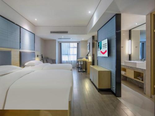 a hotel room with four beds and a sink at Echarm Hotel Beihai Railway Station in Beihai