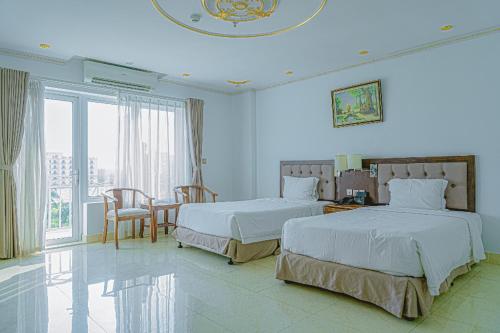 ein Schlafzimmer mit zwei Betten und einem Tisch und Stühlen in der Unterkunft Paracel Resort Hai Tien in Mỹ Ðuc