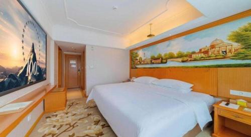 a bedroom with a large bed with a painting on the wall at Out Sky Hotel in Huizhou
