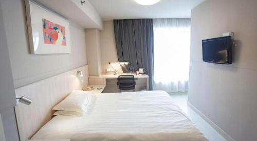 a hotel room with a bed and a desk and a television at Jinjiang Inn Wuhu Fangte Tech Museum Metro Station in Wuhu