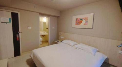 a bedroom with a white bed and a bathroom at Jinjiang Inn Wuhu Fangte Tech Museum Metro Station in Wuhu