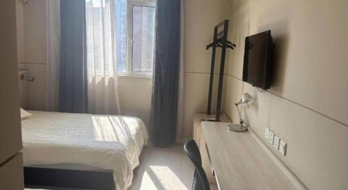 a bedroom with a bed and a desk with a television at Jinjiang Inn Pingyao Branch in Pingyao