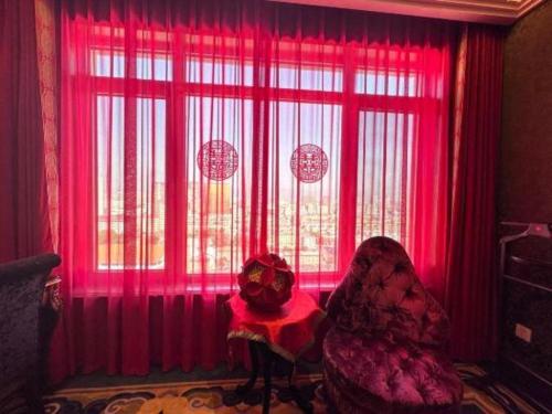 a room with red curtains and a chair in front of a window at Hohhot Inner Mongolia Hotel in Hohhot