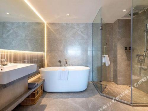 a bathroom with a tub and a sink and a shower at Overseas Chinese Hotel in Zhuhai