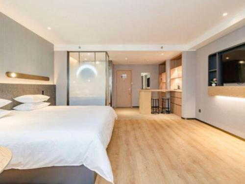 a bedroom with a large white bed and a kitchen at Jinjiang Inn Qingdao Development Zone Jinggangshan Rd. in Huangdao