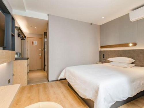 a bedroom with a large white bed and a kitchen at Jinjiang Inn Qingdao Development Zone Jinggangshan Rd. in Huangdao