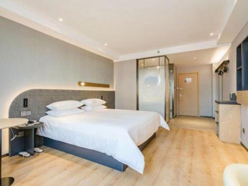 a bedroom with a large white bed and a shower at Jinjiang Inn Qingdao Development Zone Jinggangshan Rd. in Huangdao